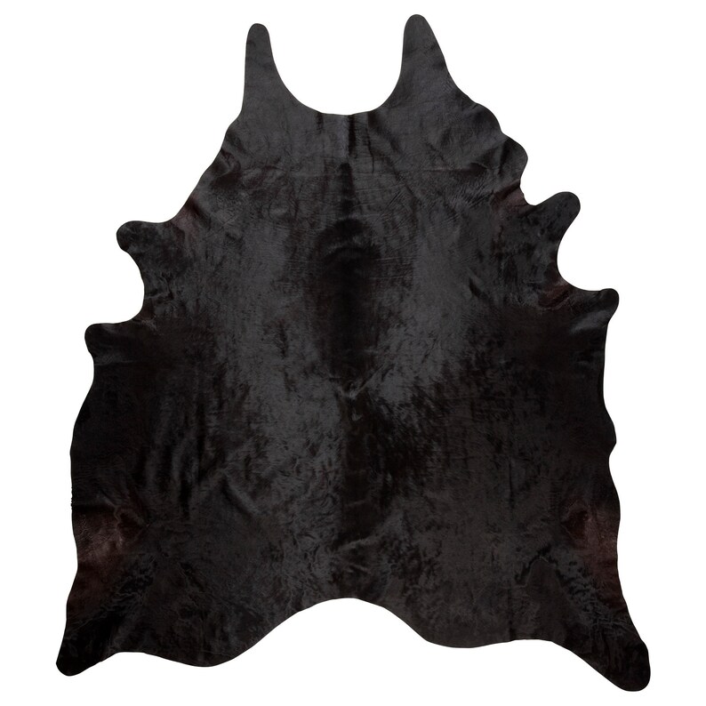 May include: Black cowhide rug with a natural, shaggy texture. The rug is approximately 5 feet by 7 feet.