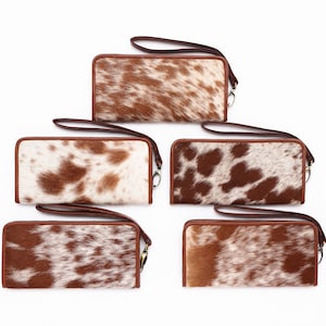 May include: Five brown and white cowhide wallets with brown leather trim and a wrist strap.