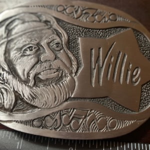 May include: Silver belt buckle with a detailed engraving of a man with a beard and the word "Willie" in a star shape.
