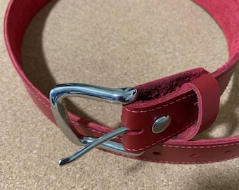 May include: A red leather belt with a silver buckle. The belt is made of a thick, durable leather and has a smooth finish.