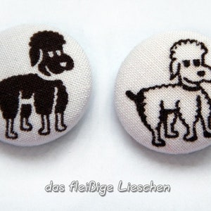 May include: Two round, white fabric buttons with a black poodle design. One button features a solid black poodle, while the other has a black outline. The text "das fleißige Lieschen" is at the bottom.