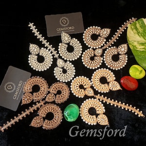 May include: Three pairs of gold and silver earrings with pearl and rhinestone embellishments. The earrings are displayed on a black surface with business cards that read "Gemsford House of Traditional Jewellery".