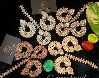 May include: Three pairs of gold and silver earrings with pearl and rhinestone embellishments. The earrings are displayed on a black surface with business cards that read "Gemsford House of Traditional Jewellery".