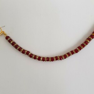 May include: A gold nose ring with a red and clear beaded chain.