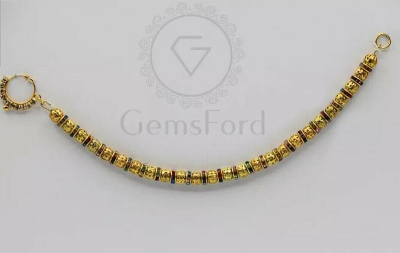 May include: A gold nose ring with a chain of small, textured beads. Each bead has a thin band of colourful enamel.