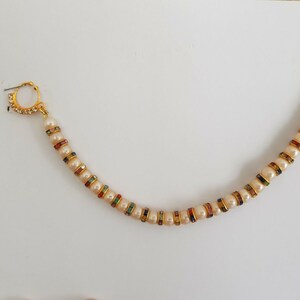 May include: A gold nose ring with a chain of white pearls and colourful rhinestones.