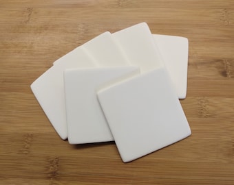 May include: Set of six white ceramic coasters. The coasters are square shaped and have a smooth, matte finish.