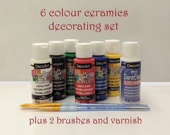 May include: A set of six 2 fl oz bottles of DecoArt Crafter's Acrylic paint in the colors white, black, green, red, blue, and yellow. The set also includes two paint brushes and a 2 fl oz bottle of Dura-Clear Gloss Varnish.