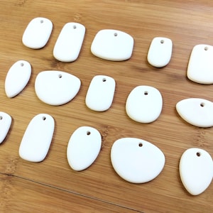 15 pendant ceramic blanks. Potluck! Various shapes and sizes similar to image but not identicle. For painting/decoupage or kiln firing.