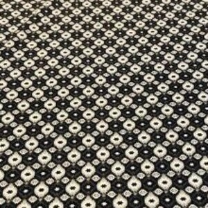 Könnte beinhalten: Schwarz-weißes Stoffmuster mit einem sich wiederholenden geometrischen Muster. Das Muster besteht aus kleinen Diamanten und Kreisen.