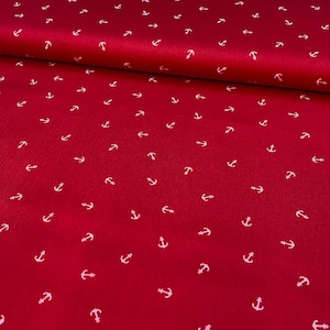Könnte beinhalten: Roter Stoff mit einem sich wiederholenden Muster aus kleinen weißen Ankern. Der Stoff ist gefaltet und zeigt einen leichten Glanz und eine Textur. Geeignet für Näh- und Bastelprojekte mit maritimem Thema.