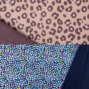 Könnte beinhalten: Zwei Stoffmuster mit unterschiedlichen Mustern. Das obere Muster ist ein hellbrauner Stoff mit einem dunkelbraunen Leopardenmuster. Das untere Muster ist ein dunkelblauer Stoff mit einem hellblauen, rosa und gelben Konfetti-Muster.
