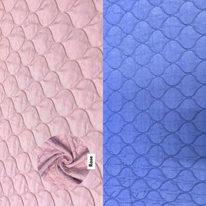 Könnte beinhalten: Zwei Stoffmuster, eines rosa und eines blau, mit einem gesteppten Muster aus sich überlappenden Ovalen. Das Wort "Rose" steht auf dem rosa Muster.