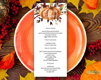 May include: A Thanksgiving menu card featuring a watercolour illustration of a pumpkin and autumn leaves. The menu includes starters, first course, main course, and dessert. The text reads "Let's give thanks".