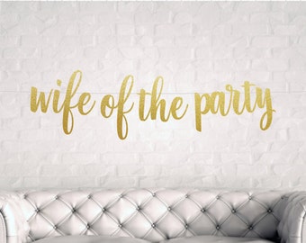 May include: Gold glitter banner with the text "wife of the party" in a cursive font.