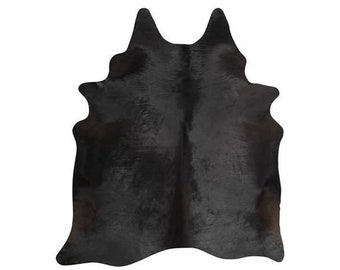 May include: Black cowhide rug with a natural, distressed look. The rug has a unique shape and a soft, supple texture.