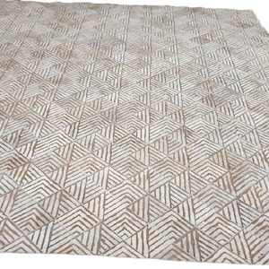 Könnte beinhalten: Ein weißer und brauner geometrischer Teppich mit einem Rautenmuster. Der Teppich hat einen dezenten Glanz und eine weiche Textur.