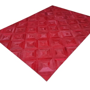 Könnte beinhalten: Ein roter Teppich mit geometrischem Muster. Der Teppich weist ein sich wiederholendes quadratisches Design mit einem helleren roten Zentrum in jedem Quadrat auf. Der Teppich ist rechteckig und scheint aus einem weichen Material zu bestehen.