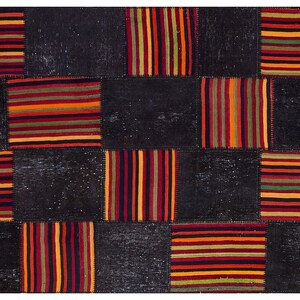 Könnte beinhalten: Ein Patchwork-Teppich mit schwarzem Hintergrund und bunten Streifenmustern in Rot-, Orange-, Gelb-, Grün- und Blautönen.