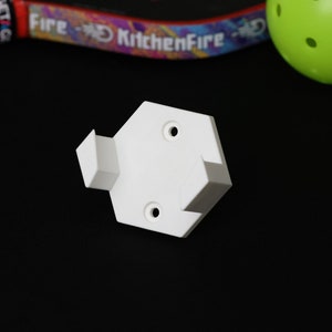 May include: White plastic corner bracket with two holes on the top and one hole on the side. The bracket is designed to be used for mounting shelves or other objects.