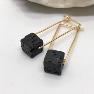 Puede incluir: Un par de pendientes de aro de oro con abalorios de cubo de roca volcánica negra.