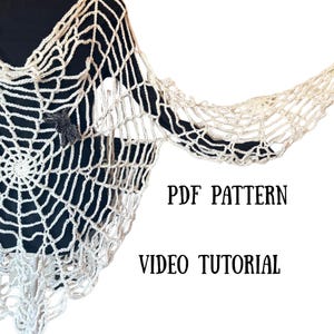May include: Cream-colored crocheted shawl with a spiderweb design and a small, dark gray spider accent. The shawl is draped over a black garment. Text on the image reads "PDF PATTERN" and "VIDEO TUTORIAL".