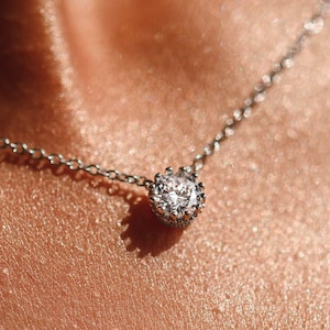 May include: A delicate silver chain necklace with a small, sparkling diamond pendant.