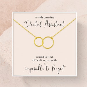 May include: A white card with a gold necklace featuring two interlocking circles. The card reads "A truly amazing Dental Assistant is hard to find, difficult to part with, & impossible to forget."