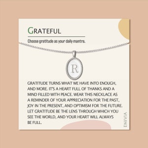 May include: A silver necklace with a round pendant that says "R" on it. The necklace comes with a card that says "GRATEFUL" and "Choose gratitude as your daily mantra." The card also includes a quote about gratitude.