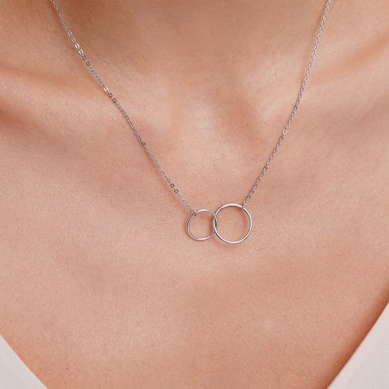 May include: A silver necklace with two interlocking circles pendant.