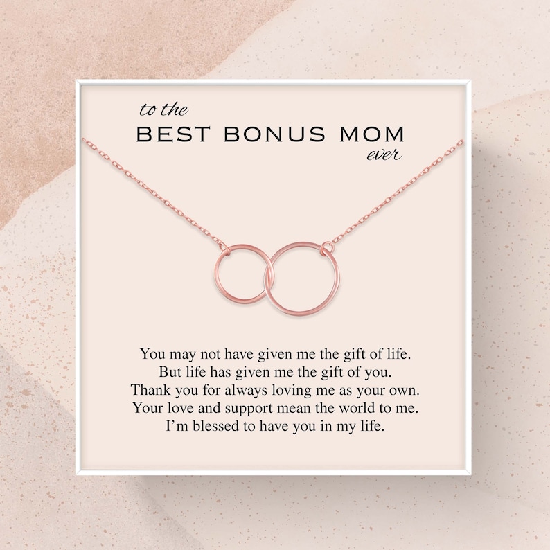 May include: A rose gold necklace with two interlocking circles, presented in a white box with a card that reads "to the BEST BONUS MOM ever". You may not have given me the gift of life. But life has given me the gift of you. Thank you for always loving me as your own. Your love and support mean the world to me. I'm blessed to have you in my life.