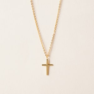 May include: A gold chain necklace with a simple gold cross pendant.