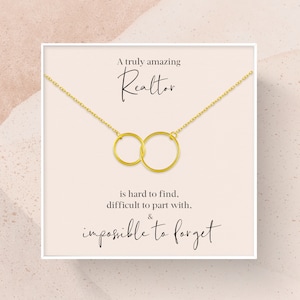 May include: A gold necklace with two interlocking circles on a white card with the text "A truly amazing Realtor is hard to find, difficult to part with, & impossible to forget."