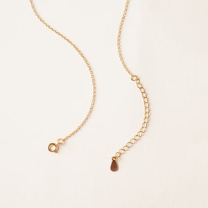 May include: A gold chain necklace with a lobster clasp and a small teardrop-shaped pendant.