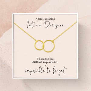 May include: A white card with a gold chain necklace featuring two interlocked circles. The card reads "A truly amazing Interior Designer is hard to find, difficult to part with, & impossible to forget."