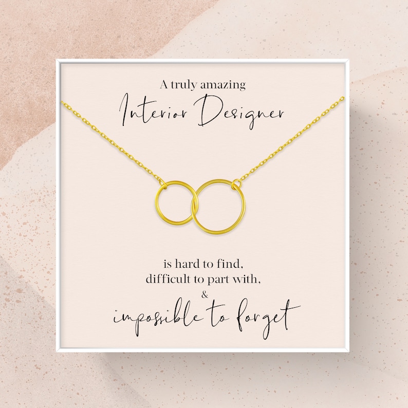 May include: A white card with a gold chain necklace featuring two interlocked circles. The card reads "A truly amazing Interior Designer is hard to find, difficult to part with, & impossible to forget."