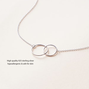 May include: A silver necklace with two interlocking circles. The necklace is made of 925 sterling silver and is hypoallergenic and safe for skin.