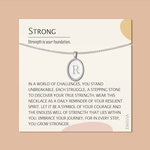 May include: A silver necklace with a round pendant that has the letter "R" on it. The necklace is on a white card with the text "STRONG" and "Strength is your foundation." The card also has text that reads "In a world of challenges, you stand unbreakable. Each struggle, a stepping stone to discover your true strength. Wear this necklace as a daily reminder of your resilient spirit. Let it be a symbol of your courage and the endless well of strength that lies within you. Embrace your journey, for in every step, you grow stronger."