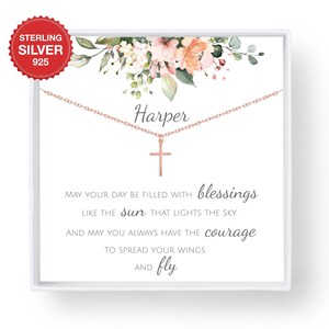 May include: A silver necklace with a cross pendant and the name "Harper" on the chain. The necklace is displayed in a white box with a floral design and the text "MAY YOUR DAY BE FILLED WITH blessings LIKE THE sun THAT LIGHTS THE SKY. AND MAY YOU ALWAYS HAVE THE courage TO SPREAD YOUR WINGS AND fly."