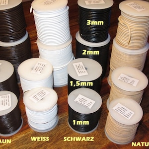 Könnte beinhalten: Spulen mit Lederkordel in verschiedenen Farben und Stärken. Farben sind Braun, Weiß, Schwarz und Natur. Die Durchmesser sind mit 1mm, 1,5mm, 2mm und 3mm angegeben. Jede Spule hat ein weißes Etikett.