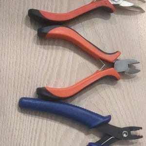 Könnte beinhalten: Drei Zangen mit schwarzen Griffen. Zwei Paare sind rot und ein Paar ist blau.