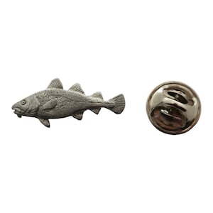 May include: A silver-toned pewter pin of a cod fish. The pin has a standard pin back.