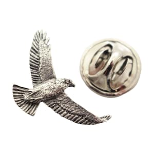 May include: A silver-colored lapel pin in the shape of a flying hawk. The pin features detailed feathering and is set against a white background. The pin has a standard pin back.
