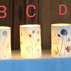 Tealight in carta velina con fiori e piante pressati come decorazione da tavola