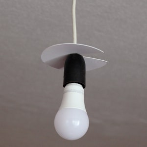 May include: A white ceiling light fixture with a white cord and a white plastic canopy. A white LED light bulb is attached to the fixture.