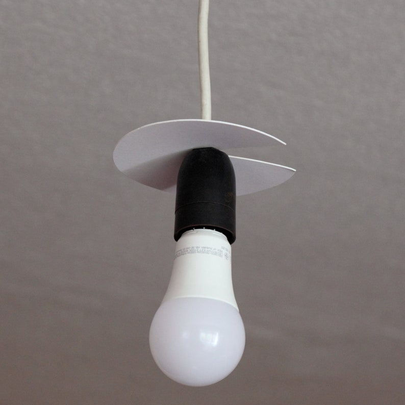 May include: A white ceiling light fixture with a white cord and a white plastic canopy. A white LED light bulb is attached to the fixture.