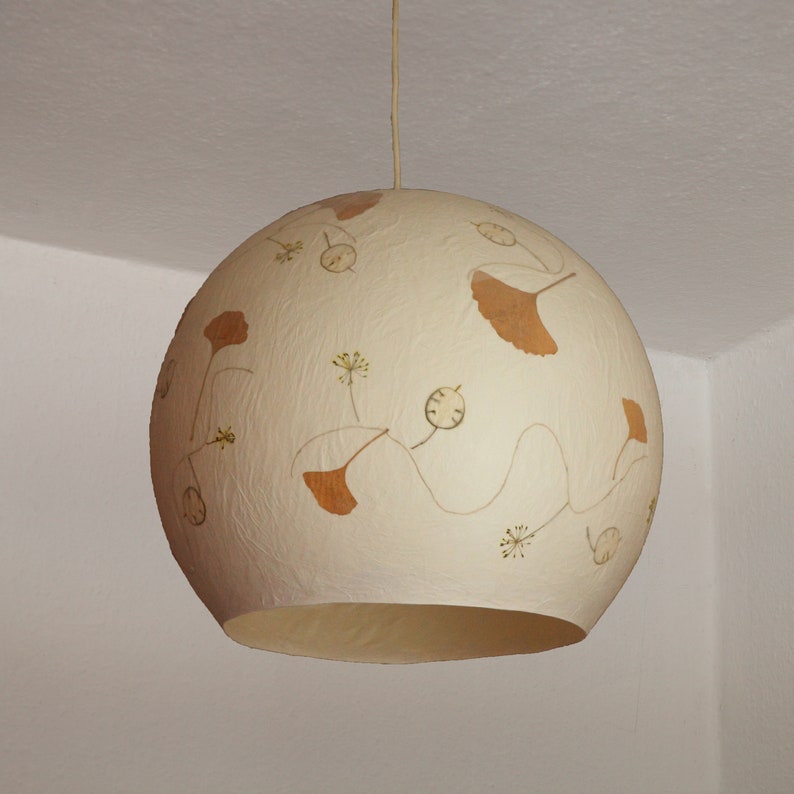 May include: A white round pendant light with a textured surface and a design of brown pressed leaves and flowers.