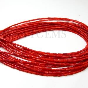 Puede incluir: Una hebra de cuentas de coral rojo, cada cuenta tiene forma rectangular. Las cuentas están enhebradas para formar un collar largo.