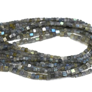 May include: A strand of dark gray square-shaped labradorite beads with iridescent shimmer.