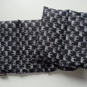 Könnte beinhalten: Drei schwarze Stoff-Wärmepads mit einem weißen Elefantenmuster. Die Wärmepads sind rechteckig und haben ein Etikett mit der Aufschrift "Mara's".